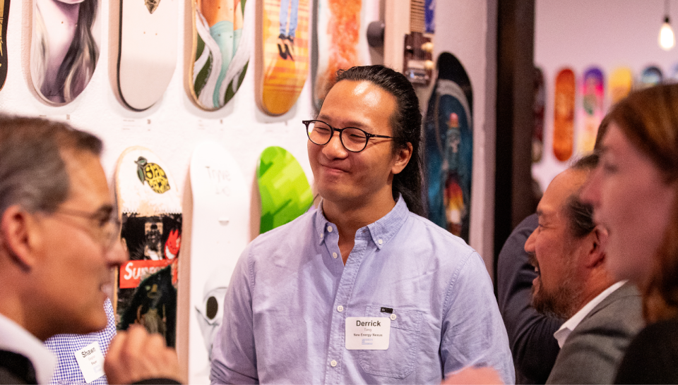 Derrick Tang, the program director for New Energy Nexus California standing in front of colorful skateboards.